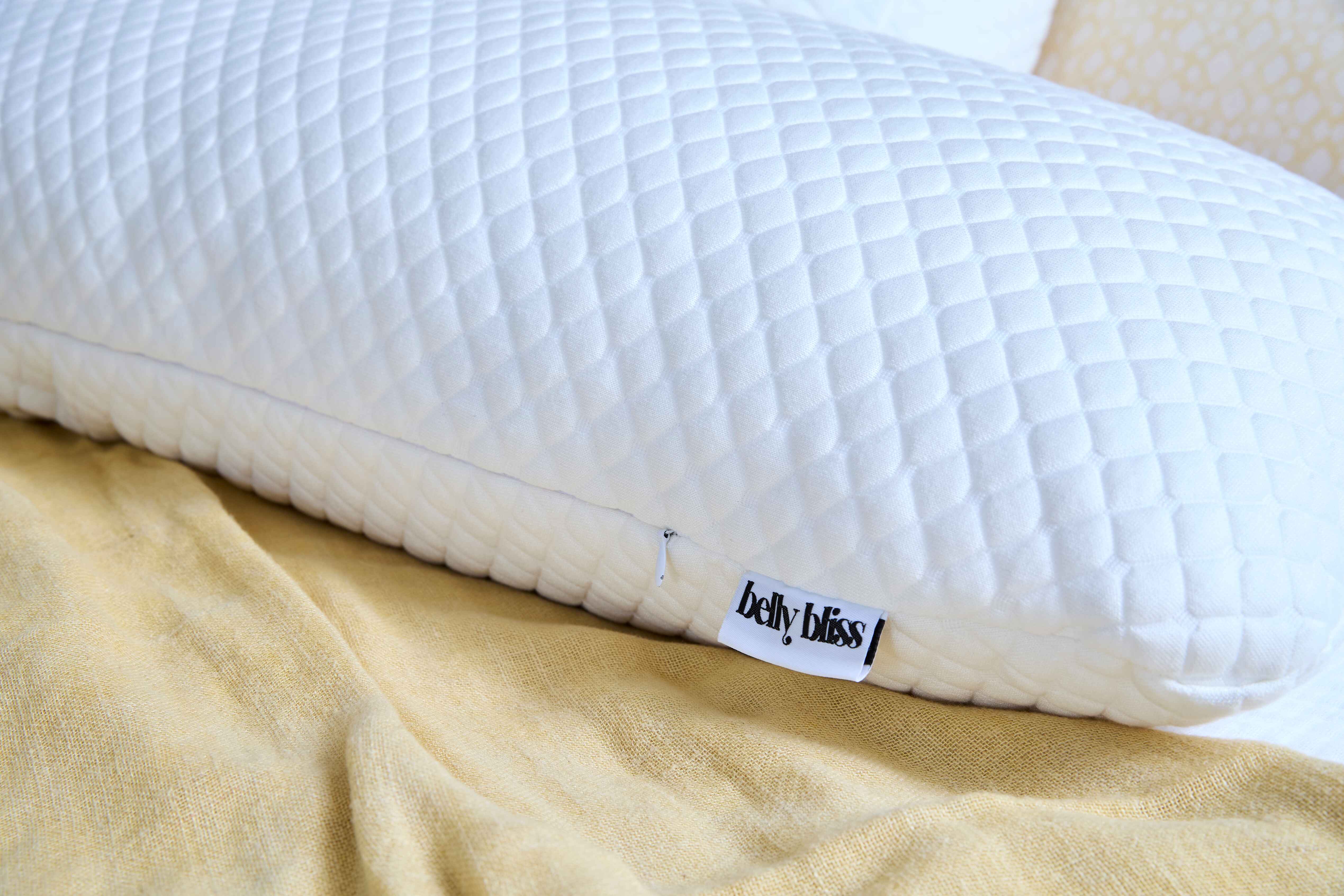 close up of belly bliss pregnancy pillow on yellow blanket