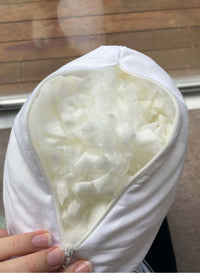 White pillow with a zipper open held by a hand against a wooden background