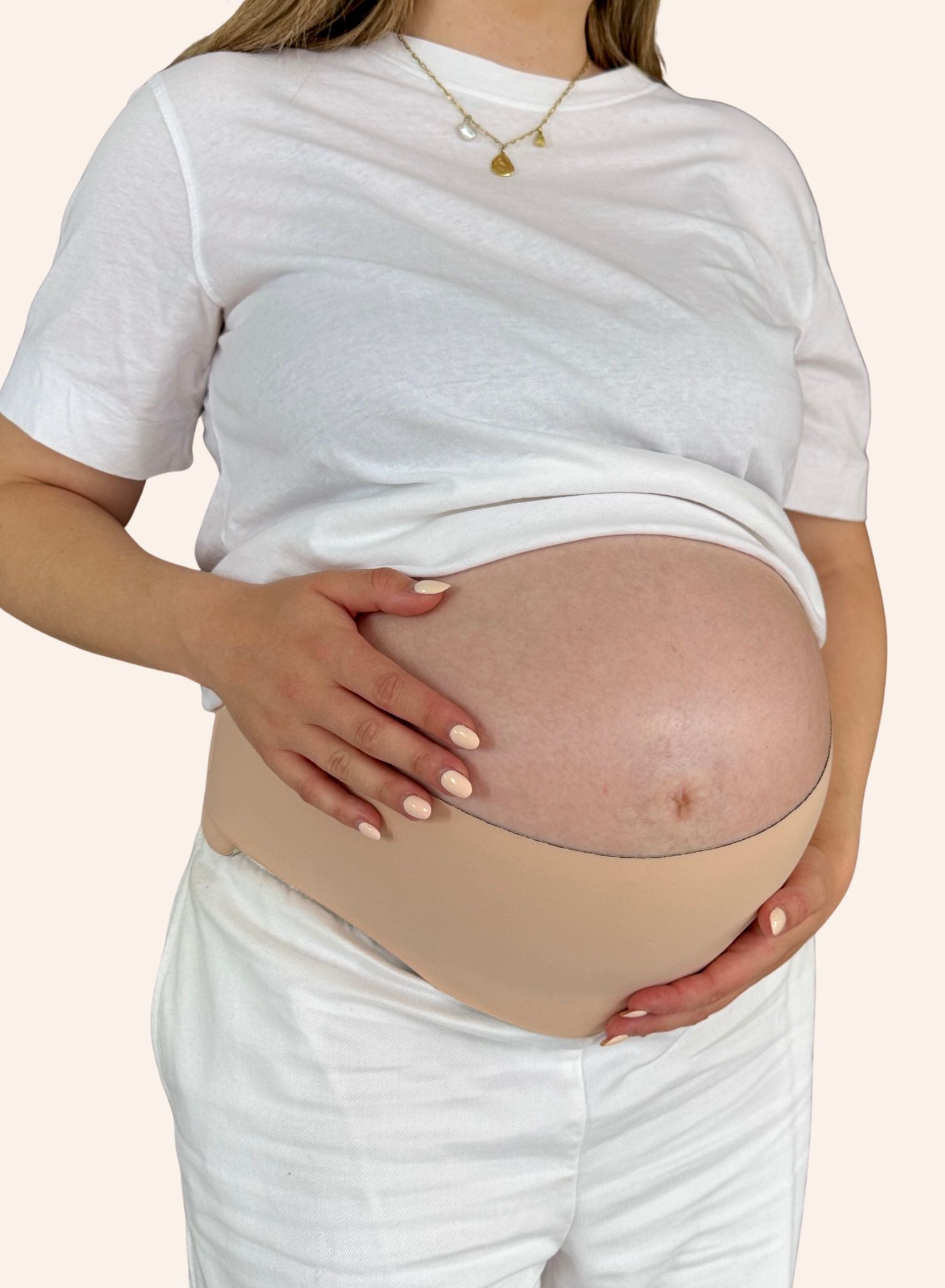 Pregnant person wearing a beige belly band on a plain background