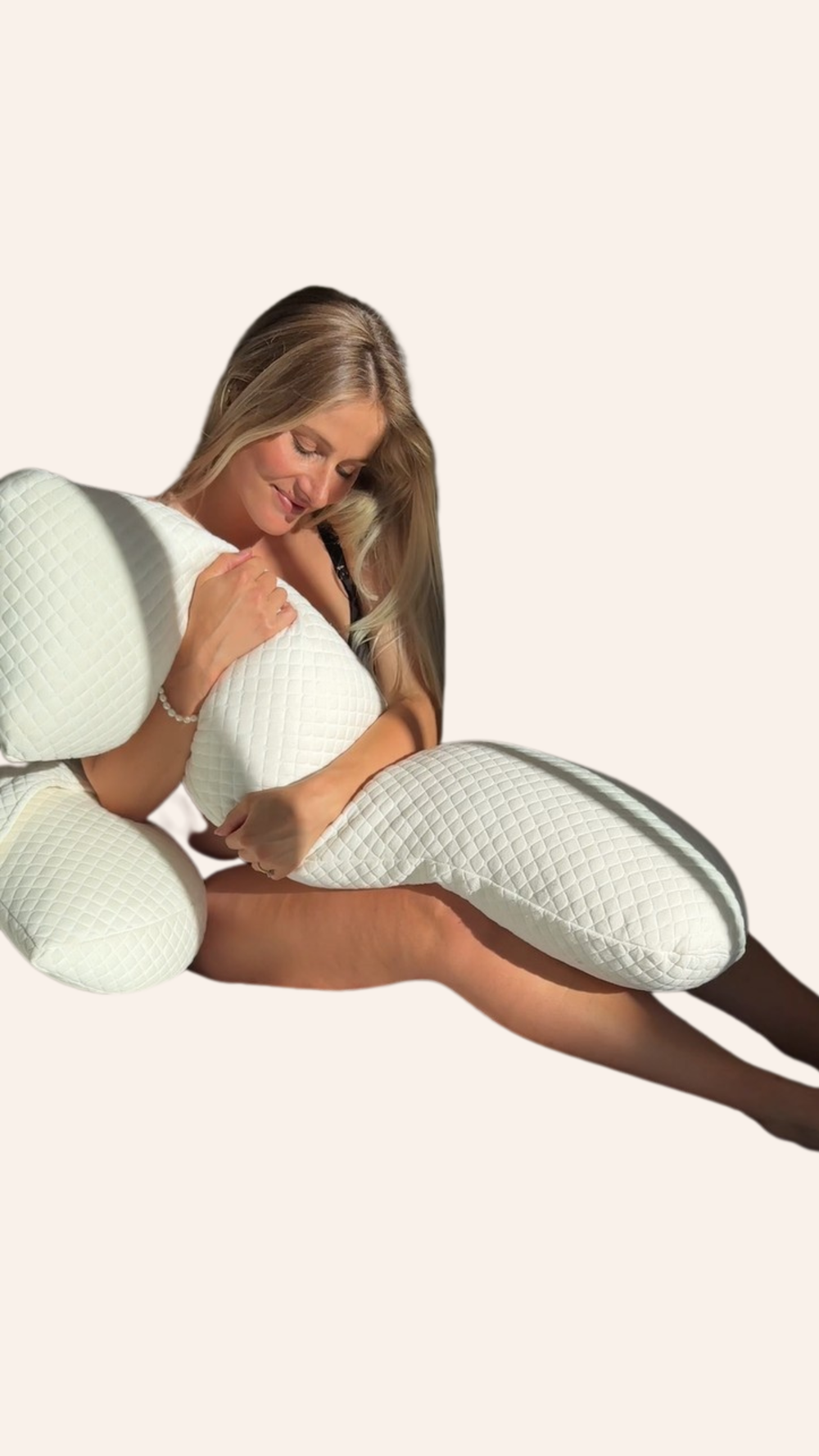 Woman cuddling pregnancy pillow on a plain background