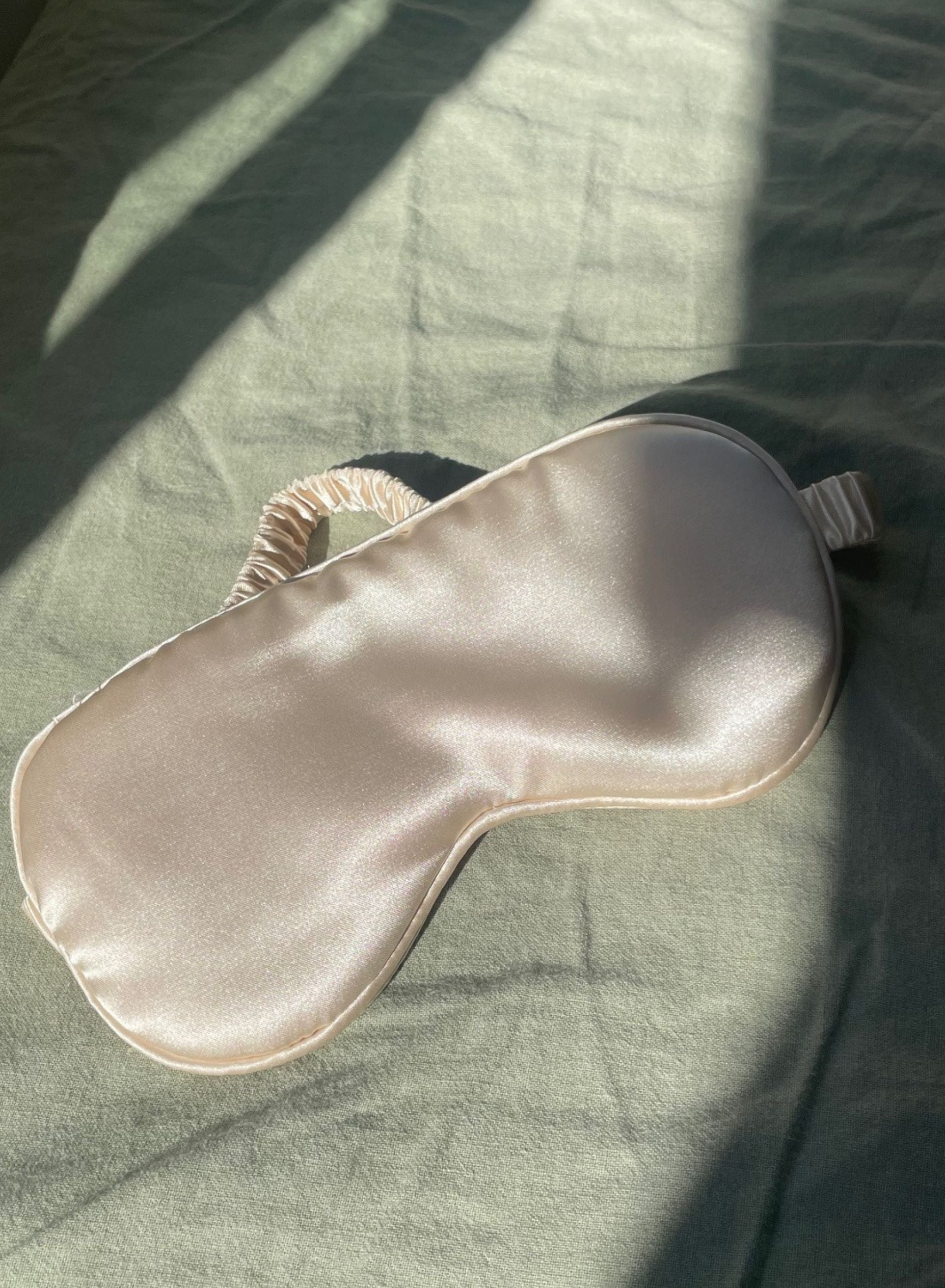 Silky sleep mask on a textured green fabric surface