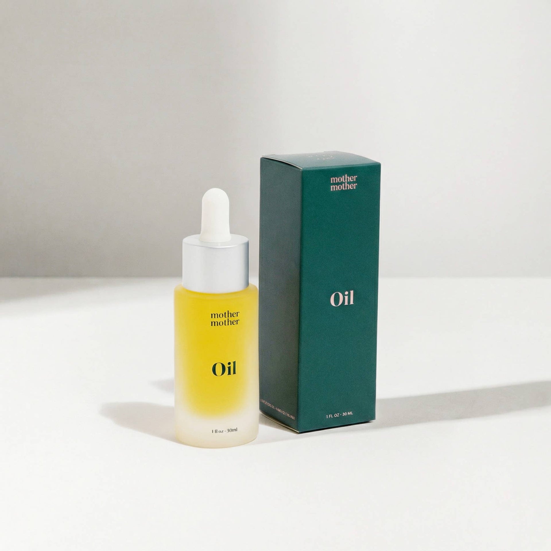 Bottle of 'mother mother' oil with a matching box on a white background