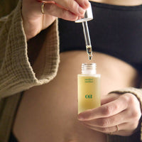 Person holding a bottle of 'mother mother' oil with a dropper.