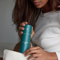Person holding a blue bottle labeled 'Magnesium Oil' against a neutral background
