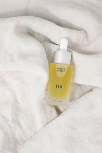 Skincare dropper bottle with yellow liquid on a white fabric background