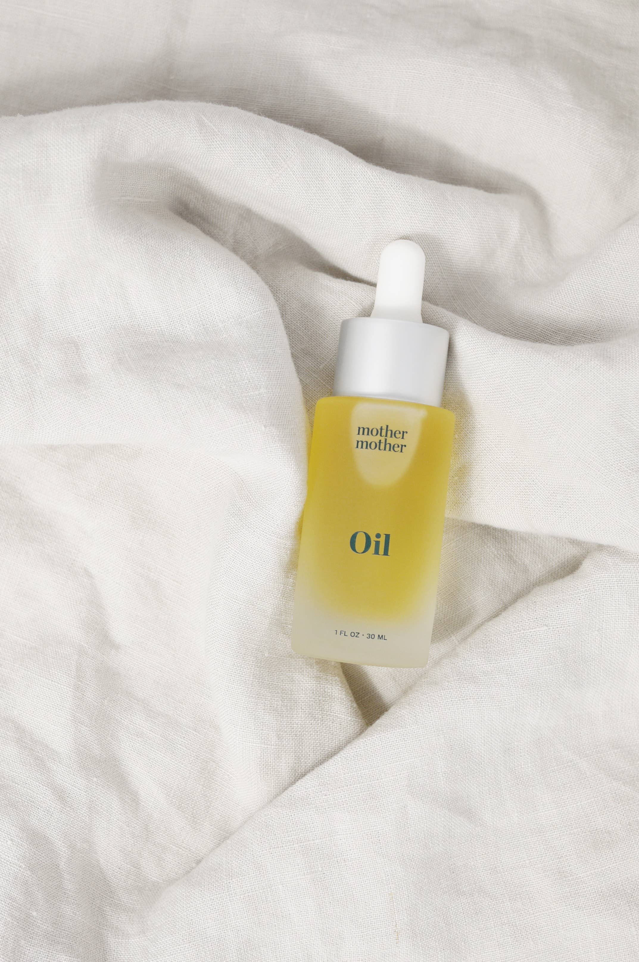 Skincare dropper bottle with yellow liquid on a white fabric background