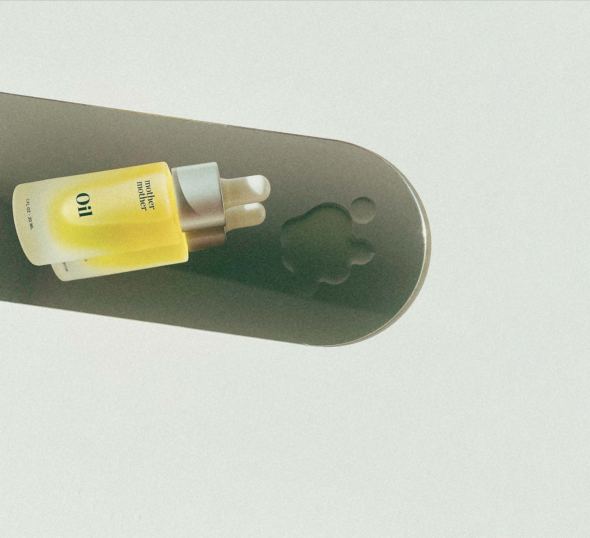 Yellow bottle labeled 'Oil' on a gray surface with a paw print