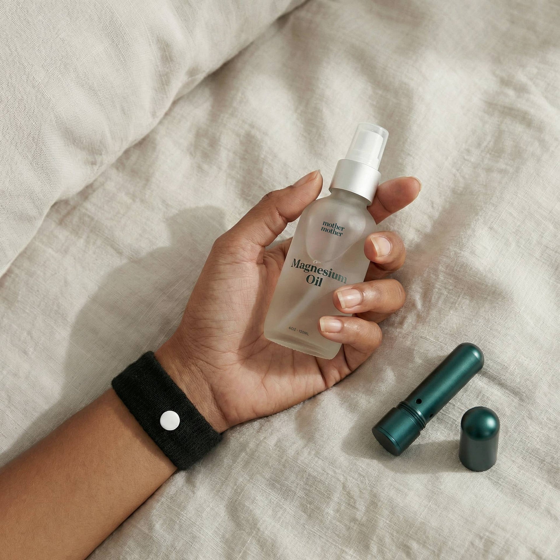 Hand holding a bottle of magnesium oil on a textured surface