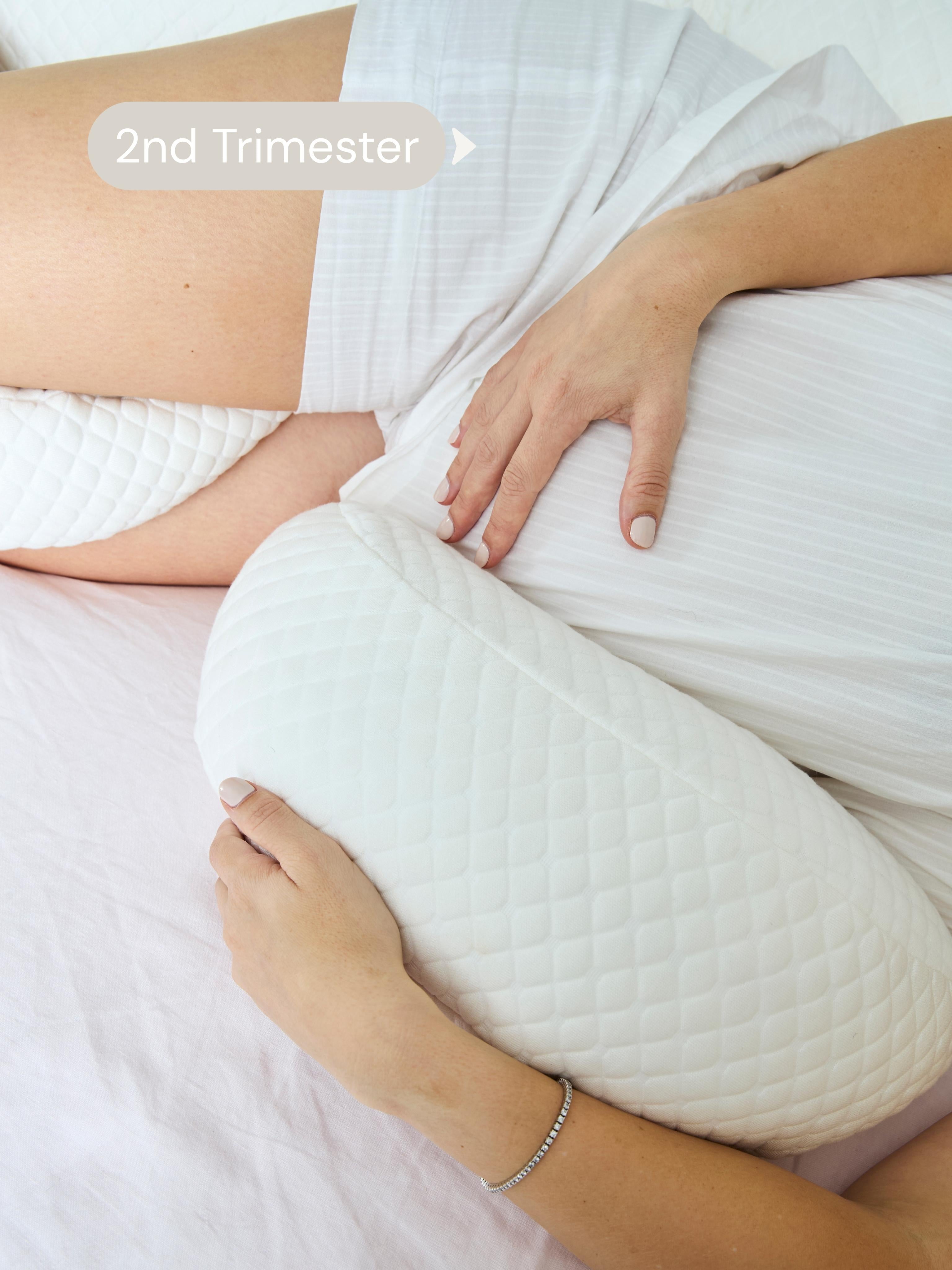 Pregnant person using a white pillow during the 2nd trimester.